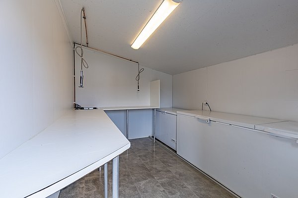 Küchenzeile mit Arbeitsflächen, Hängelampen und geräumigen Gefrierschränken in nordnorwegischer Angelhütte. Ideal zum Zubereiten und Lagern des gefangenen Fisches. Perfekt für Angelreisen in Norwegen.