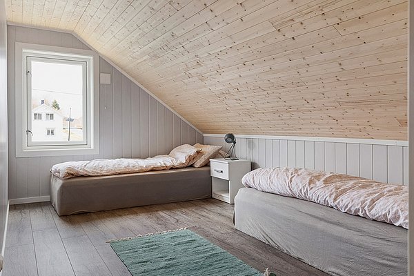 Gemütliches Schlafzimmer mit Holzdecke in Nordland, Norwegen. Zwei Einzelbetten, Fensterblick auf Fjordlandschaft. Idealer Rückzugsort für Angelabenteuer. Skandinavisches Design, ruhige Atmosphäre. Perfekt für erholsame Nächte nach einem erfolgreichen Angelausflug.