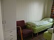 Gemütliches Zimmer im Nordland, Norwegen: Einzelbett mit grüner Bettwäsche, roter Sessel, weißer Kleiderschrank und Holzboden. Perfekt für eine erholsame Angelreise.