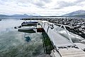 Fjordblick in Nord-Norwegen: Boote am Steg, klare Gewässer, umrahmt von majestätischen Bergen und grauem Himmel. Ideal für Angelreisen und Naturerlebnis.