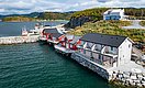 Gemütliche rote Holzhäuser am Wasser in Hitra, Norwegen, umgeben von üppiger Landschaft. Perfekter Ausgangspunkt für Angelabenteuer und Erholung am Meer. Ruhige Atmosphäre und atemberaubende Aussicht bieten ideale Bedingungen für unvergessliche Angelreisen.