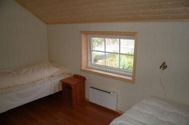Gemütliches Schlafzimmer in einer Holzhütte in Nordland, Norwegen. Zwei Einzelbetten, Holzdecke, Fenster mit Blick ins Grüne. Ideal für Angelurlauber, die Natur und Entspannung suchen.