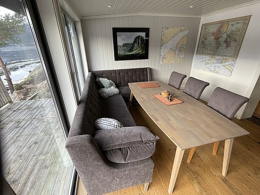 Dieses gemütliche Wohnzimmer in Südwest-Norwegen bietet mit seiner Panoramaglasfront einen atemberaubenden Blick auf die Küstenlandschaft. Perfekt für entspannte Angelreisen und gemütliche Abende mit Blick aufs Wasser. Ideal für Natur- und Angelurlaub.
