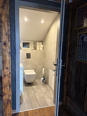 Sauberes, modernes Badezimmer in Nord-Norwegen, gefliest mit Schiebetür und Holzbalken. Bequemer Zugang nach Angelabenteuern in der Region. Ideal für einen komfortablen Angelurlaub.