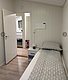 Gemütliches Schlafzimmer mit Einzelbett, modernem Nachttisch und Tür zum Badezimmer. Helle Holzwände und -böden schaffen eine einladende Atmosphäre. Ideale Unterkunft für Angelurlaub in der Region Hitra, Norwegen.