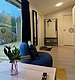Gemütlich eingerichtetes Zimmer in Hitra, Norwegen, mit modernem Dekor, bequemer Sitzgelegenheit und großem Fenster, das den Blick ins Grüne freigibt. Ideal für entspannte Angelurlaube in natürlicher Umgebung.