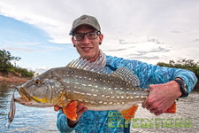 Ein Angler hält einen prächtigen Fisch mit leuchtenden Flossen vor einem ruhigen Gewässer in Südwest-Norwegen. Ideales Ziel für Angelreisen mit beeindruckenden Fangmöglichkeiten. Perfekt für Abenteuer und Entspannung in der Natur.