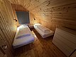 Gemütliches Schlafzimmer in einer Hütte auf Hitra, Norwegen. Zwei Einzelbetten, Holzverkleidung und schräges Dach schaffen eine warme Atmosphäre. Perfekt für entspannte Angelurlaube.