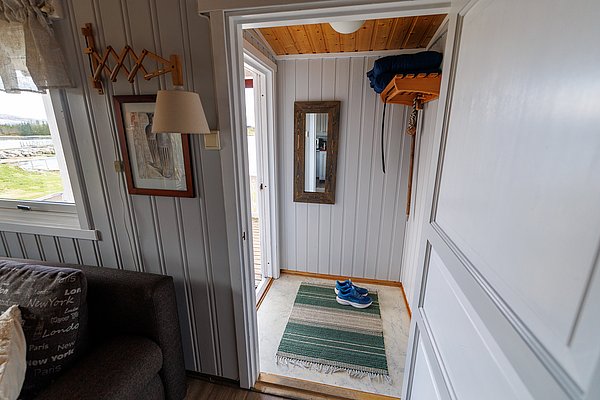Gemütlicher Flur in einem Ferienhaus auf Hitra, Norwegen. Holzwände, Teppich und moderne Einrichtung schaffen eine einladende Atmosphäre für Angelreisende. Ideal für erholsamen Angelurlaub in schöner Umgebung.