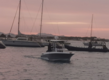 Boote im Hafen von São Vicente, Kapverden bei Sonnenuntergang. Ruhiges Wasser, rosafarbener Himmel, Segelboote und ein Motorboot schaffen eine malerische maritime Szene, ideal für entspannte Momente oder Angelreisen in exotischer Umgebung.