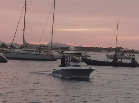 Boote im Hafen von São Vicente, Kapverden bei Sonnenuntergang. Ruhiges Wasser, rosafarbener Himmel, Segelboote und ein Motorboot schaffen eine malerische maritime Szene, ideal für entspannte Momente oder Angelreisen in exotischer Umgebung.