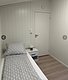 Einladendes Einzelzimmer in Hitra, Norwegen, mit hellem Holzinterieur. Gemütliche Bettwäsche und Nachttischlampe bieten Komfort für Angelreisende. Ideal für erholsame Nächte nach einem Tag voller Abenteuer.