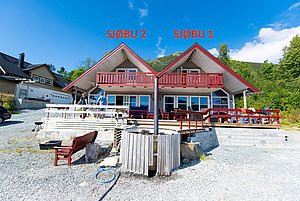 Zwei charmante Ferienhäuser in Südwest-Norwegen mit roten Dachgiebeln und Balkonen, umgeben von grüner Natur. Perfekt für einen entspannenden Angelurlaub in Norwegen. Ideal für Erholung und Entdeckungen in atemberaubender Landschaft.