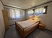 Gemütliches Schlafzimmer mit Holzbett und sanfter Beleuchtung in Hitra, Norwegen. Ideal für entspannte Angelreisen. Lichtdurchfluteter Raum mit Vorhängen für Privatsphäre. Perfekter Rückzugsort nach einem langen Angeltag.