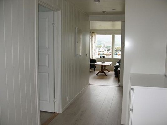 Heller Flur eines Ferienhauses in Nordland, Norwegen. Blick auf ein gemütliches Wohnzimmer mit großen Fenstern, die einen malerischen Ausblick auf den Hafen bieten. Perfekter Ausgangspunkt für Angelreisen.