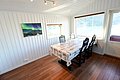 Helles Esszimmer mit Blick auf norwegischen Fjord in Nord-Norwegen, dekoriert mit Polarlicht-Foto. Ideal für entspannten Angelurlaub. Große Fenster und Holzboden schaffen gemütliches Ambiente.