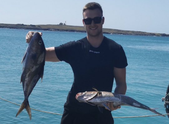Ein Angler präsentiert stolz zwei gefangene Fische vor der atemberaubenden Küste von São Vicente, Kapverden. Perfektes Ziel für Angelurlaub und Meeresangeln. Petri Heil!