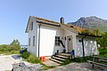 Weißes Landhaus mit begrüntem Dach in Nordland, Norwegen, vor majestätischer Bergkulisse. Ideal für Angelurlaub am Fjord. Nachhaltige Architektur im Einklang mit der Natur. Perfekter Rückzugsort für Outdoor-Abenteuer und Entspannung.