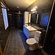 Modernes Badezimmer in Nord-Norwegen mit schwarzer Fliesenoptik, weißem Waschbecken und WC. Stilvolle Beleuchtung sorgt für harmonische Atmosphäre. Perfekt für einen komfortablen Angelurlaub in skandinavischem Design.