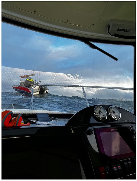 Ein Unwetter auf See, aufgenommen durch die Frontscheibe eines Bootes, zeigt ein weiteres Boot, das in unruhigen Wellen kämpft.
