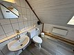 Ein gemütliches, helles Badezimmer in einer Angelhütte in Hitra, Norwegen, mit Holzwänden, Waschbecken, Toilette und Spiegelschrank. Ideal für einen komfortablen Angelurlaub.
