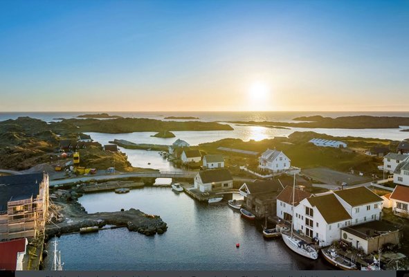 Luftaufnahme eines malerischen Küstendorfs mit weißen Häusern und kleinen Booten im Hafen, während die Sonne am Horizont über dem Meer untergeht. Luftaufnahme eines malerischen Küstendorfs mit weißen Häusern und kleinen Booten im Hafen, während die Sonne am Horizont über dem Meer untergeht.
