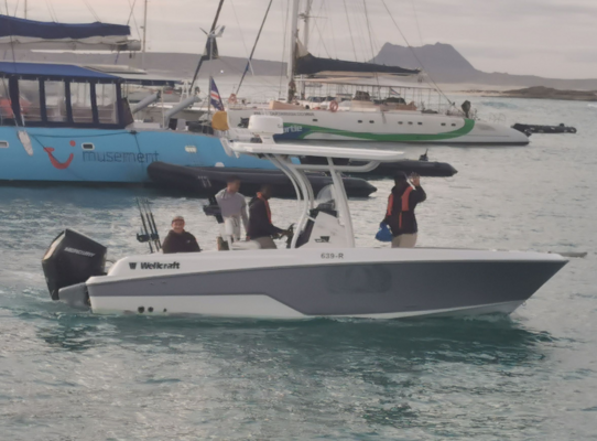 Sportboot in der Bucht von São Vicente, Kapverden. Im Hintergrund segeln größere Boote, umgeben von Meer und sanften Hügeln. Perfektes Ziel für Angelreisen und Meeresabenteuer.