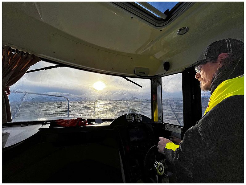 Bootsfahrt auf dem River Shannon, Irland: Ein Angler steuert ein Hausboot bei Sonnenuntergang. Die Szene spiegelt Abenteuer und Ruhe wider, ideal für Angelreisen. Wellen und Lichtspiele schaffen eine atmosphärische Stimmung.