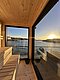 Sauna mit Holzverkleidung in Südwest-Norwegen, bietet atemberaubenden Blick auf den Sonnenuntergang über dem Wasser. Ideal für Entspannung nach einem Angeltag. Perfekte Mischung aus Naturerlebnis und Luxus.