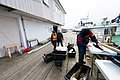 Ein Angler filetiert Fisch auf einem norwegischen Holzsteg neben Booten. Die Szene zeigt einen erfolgreichen Angelurlaub in Nordland, Norwegen, mit frischem Fang und maritimem Ambiente.