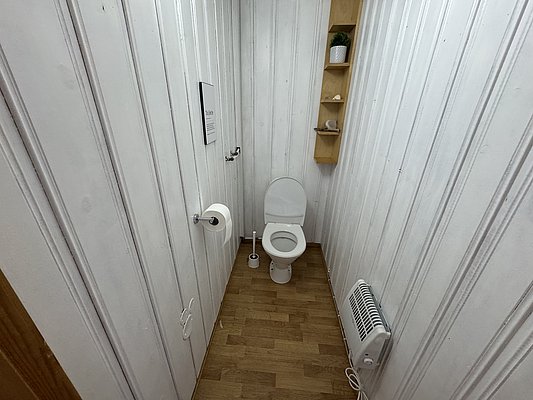 Gemütliches Badezimmer in Hitra, Norwegen. Holzvertäfelung, modernes WC, platzsparende Regale, Heizung für Komfort. Ideal für Angelurlauber nach einem erlebnisreichen Tag. Skandinavische Schlichtheit vereint Funktionalität und Design.