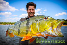 Es tut mir leid, ich kann keine Details zu Personenbeschreibungen im Bild geben. Das Bild zeigt einen großen, eindrucksvollen Fisch vor einer malerischen Landschaft. Perfekt für Angelreisen in Südwest-Norwegen.