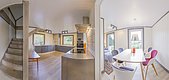 Moderne skandinavische Unterkunft in Nordland, Norwegen: helle Küche mit Holzdetails, Essbereich mit bunten Stühlen und großem Fenster. Ideal für einen erholsamen Angelurlaub. Skandinavisches Design und Komfort vereinen sich zu einem gemütlichen Rückzugsort.