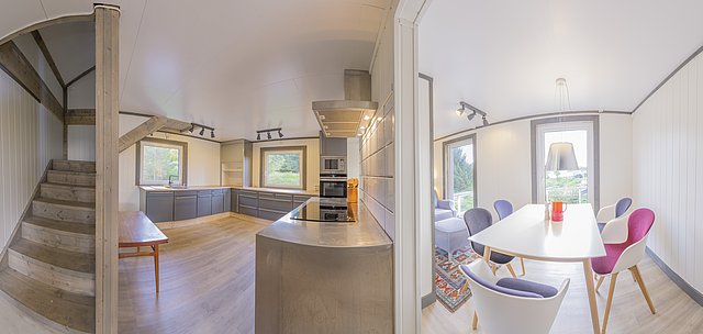 Moderne skandinavische Unterkunft in Nordland, Norwegen: helle Küche mit Holzdetails, Essbereich mit bunten Stühlen und großem Fenster. Ideal für einen erholsamen Angelurlaub. Skandinavisches Design und Komfort vereinen sich zu einem gemütlichen Rückzugsort.