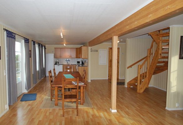 Gemütliches Ferienhaus in Hitra, Norwegen: Offener Wohn- und Essbereich mit Holzmöbeln, moderner Küche, Holztreppe, großen Fenstern und viel natürlichem Licht – ideal für entspannten Angelurlaub.