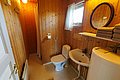 Holzvertäfeltes Badezimmer in Hitra, Norwegen. Ausstattung: kleine Dusche, Toilette, Waschbecken, Spiegel, Handtücher. Gemütlich und funktional für Angelurlauber. Natürliche Materialien schaffen rustikales Ambiente in skandinavischem Stil. Perfekt für Abenteuer mit Komfort.