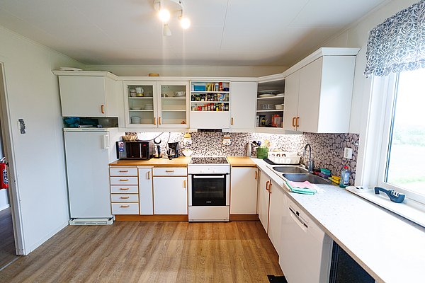 Helle, gemütliche Küche in Nord-Norwegen mit modernen Geräten und Blick auf die malerische Landschaft. Ideal für entspannte Angelurlaube mit hochwertiger Ausstattung. Perfekte Kombination aus Komfort und Natur.