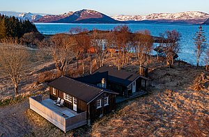Gemütliche Holz-Hütte in Nordland, Norwegen, mit Blick auf verschneite Berge und Küste. Perfekt für Angelurlaub und Naturerlebnisse. Klare Luft und atemberaubende Landschaft laden zum Verweilen ein. Abgeschieden und idyllisch gelegen.