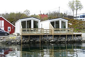 Moderne Ferienhäuser auf Hitra, Norwegen, direkt am Wasser. Perfekt für Angelurlaub und Naturerlebnisse. Holzterrassen bieten Ausblick auf felsige Küsten und das Meer. Ideal für Erholung und Abenteuer in malerischer Umgebung.