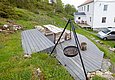 Holzterrasse in Hitra, Norwegen mit rustikalen Sitzmöbeln und einem Grillplatz, umgeben von grüner Natur. Perfekt für einen gemütlichen Angelurlaub und entspannende Stunden im Freien. Ideal gelegen, um die Schönheit Norwegens zu genießen.