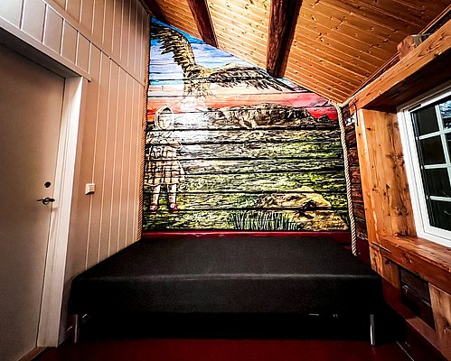 Holzverkleidetes Zimmer mit rustikalem Wandgemälde eines Adlers und eines Kindes, gemütliches Ambiente, idealer Rückzugsort in Hitra, Norwegen. Perfekt für Angelurlauber, die Natur und Kunst lieben.