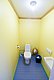 Heller, kompakter Toilettenraum in Nordland, Norwegen, mit gelben Wänden und blauen Bodenfliesen, ausgestattet mit Toilette, Waschbecken und Toilettenartikeln – ideal für komfortable Angelreisen.