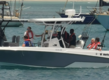 Motorboot vor Sao-Vicente, Kapverden: Fünf Personen in Schwimmwesten genießen das Angelerlebnis auf dem Meer. Ideal für Angelreisen, Abenteuer und Entspannung in malerischer Küstenlandschaft, umgeben von blauen Wellen.