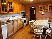 Gemütliche norwegische Landhausküche auf Hitra: Holzmöbel, moderner Herd, Esstisch mit Stühlen, weiß gefliester Spritzschutz, hölzerne Decke und rustikaler Charme. Perfekt für Entspannung nach einem erfolgreichen Angeltag in der Region Hitra.