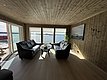 Gemütliches Wohnzimmer mit Ledersofas und Panoramablick auf das Meer. Helle Holzverkleidung ergänzt die skandinavische Atmosphäre. Perfekter Rückzugsort in Hitra, Norwegen, ideal für entspannende Angelreisen.