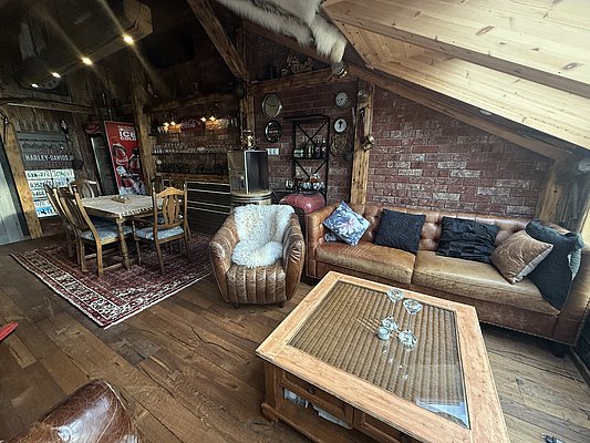 Gemütlicher Wohnbereich in Nord-Norwegen, Norwegen mit rustikalen Holzmöbeln, Ledersofas und gemütlicher Beleuchtung; perfekte Atmosphäre für Angelurlauber. Holzboden und Backsteinwände verleihen nordischen Charme. Ideal zum Entspannen nach einem Tag am Fjord.