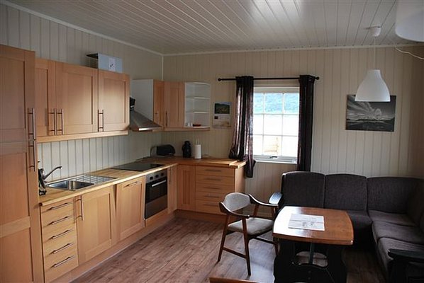 Gemütliche Ferienhausküche in Nordland, Norwegen, mit moderner Einbauküche, Esstisch und Sofa. Perfekt für Angelabenteuer und Erholung in idyllischer Umgebung. Ideal für Angelreisen und Naturliebhaber.