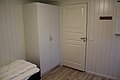 Ein gemütliches Zimmer in Nord-Norwegen mit Holzfußboden, weißem Kleiderschrank und einer Tür. Ideal für Erholung nach einem ereignisreichen Angelurlaub in Norwegen. Klare, ruhige Atmosphäre.