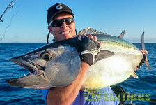 Ein stolzer Angler hält einen großen Thunfisch vor der malerischen Küste Tansanias. Perfektes Meeresangeln-Abenteuer unter sonnigem Himmel. Ideal für leidenschaftliche Angler, die exotische Fischarten und unvergessliche Erlebnisse suchen.