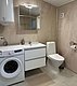 Modernes Badezimmer in Hitra, Norwegen, mit Waschmaschine, Waschbecken, Spiegel und Toilette. Helle Fliesen und saubere Ausstattung bieten Komfort für Angler während ihres Angelurlaubs. Perfekt für Erholung nach einem erfolgreichen Tag am Wasser.